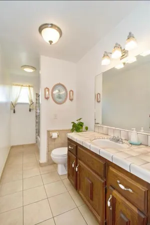 a spacious bathroom with a granite countertop sink a toilet and a mirror
