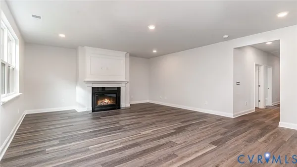 a view of an empty room with wooden floor fireplace and a window