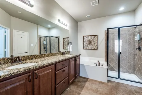 a bathroom with a granite countertop double vanity sink a mirror and a bathtub