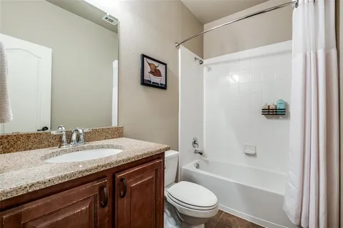 a bathroom with a granite countertop sink a toilet and shower