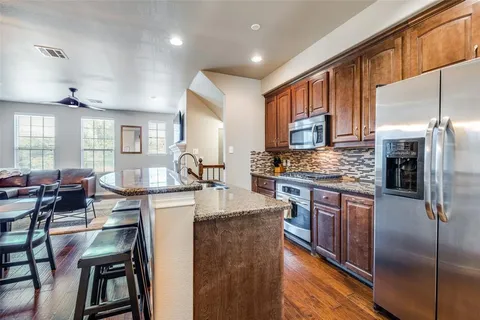 a kitchen with stainless steel appliances granite countertop a stove refrigerator sink and chairs