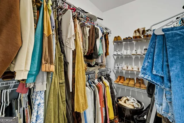 a view of walk in closet with clothes and shoes