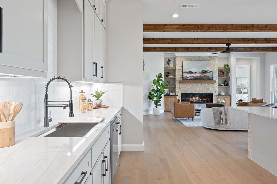 713 San Gabriel Ranch Road Liberty Hill, TX 78642 - Photo 11 of 40 a kitchen with kitchen island a counter top space a sink stove and white cabinets with wooden floor