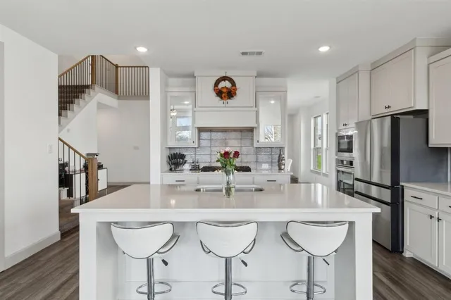 a kitchen with kitchen island granite countertop a sink cabinets and wooden floor
