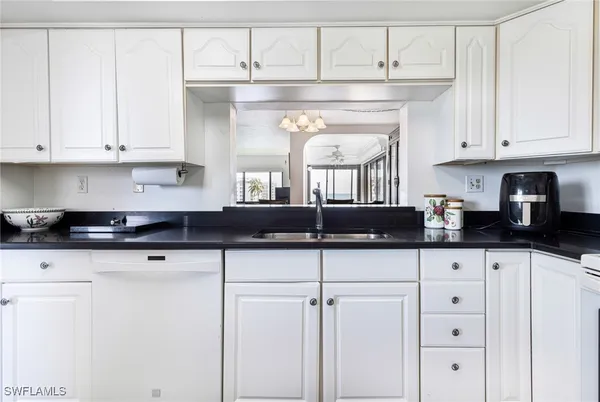 a kitchen with granite countertop white cabinets and white appliances