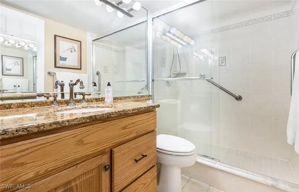 a bathroom with a granite countertop sink mirror vanity and toilet