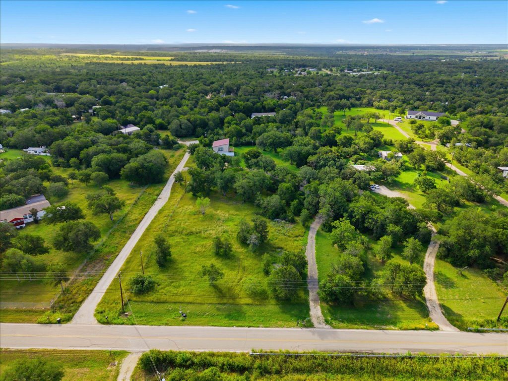 211 Webberwood Way Elgin, TX 78621 - Photo 1 of 10 An aerial perspective reveals a vast, tree-filled landscape with scattered homes and clearings, hinting at rural serenity.
