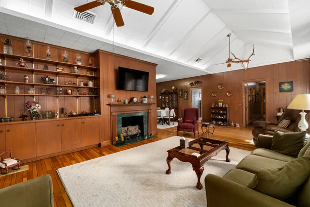 a living room with furniture a flat screen tv and floor to ceiling window