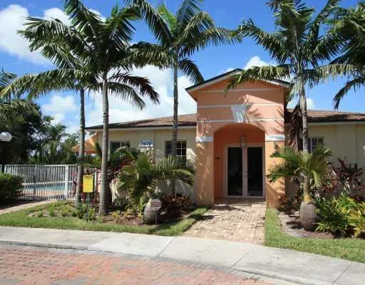 front view of house with a yard and palm trees