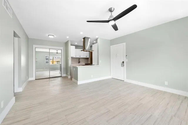 an empty room with wooden floor cabinet and windows