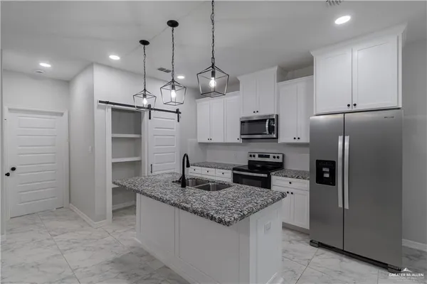 a kitchen with stainless steel appliances granite countertop a sink a refrigerator and a stove top oven