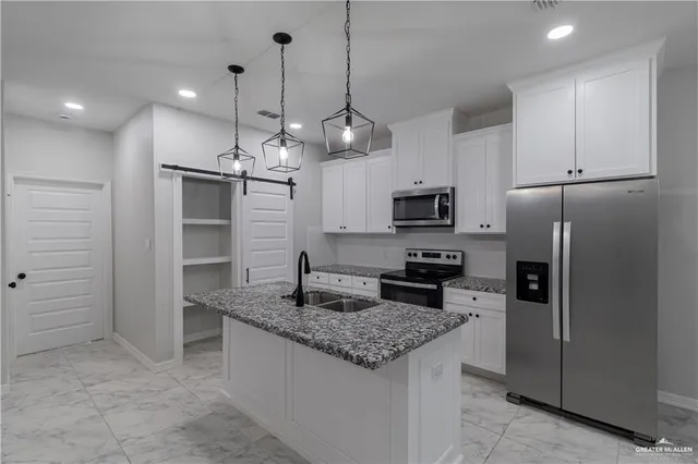 a kitchen with stainless steel appliances granite countertop a sink a refrigerator and a stove top oven