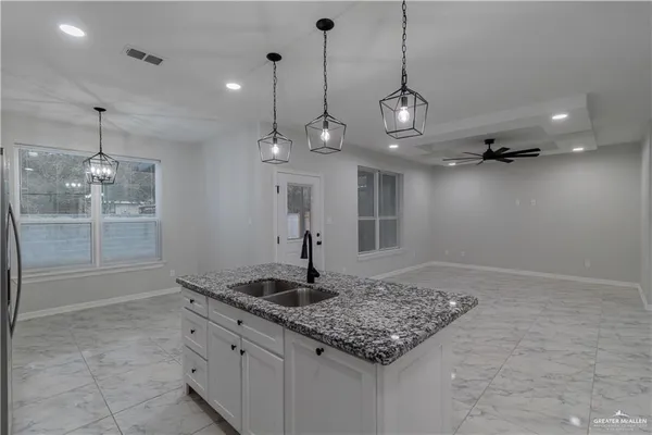 a kitchen with kitchen island granite countertop cabinets a sink a island and windows