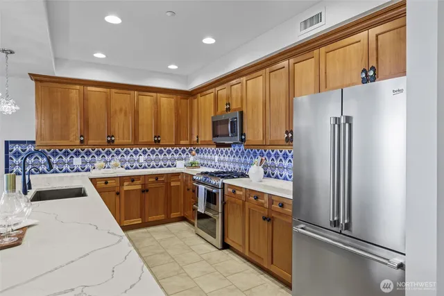 a kitchen with stainless steel appliances granite countertop a refrigerator and a sink