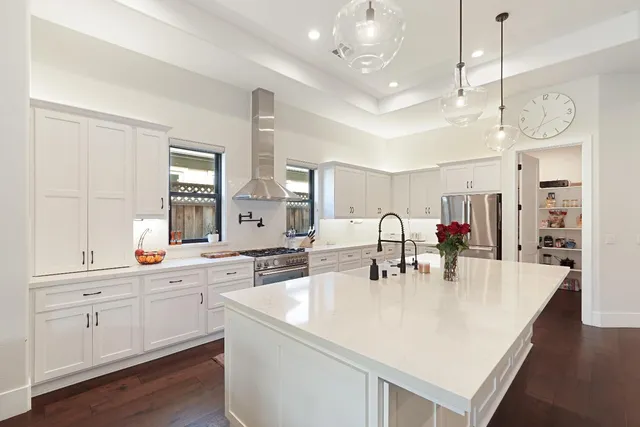 a large white kitchen with lots of counter space and chandelier