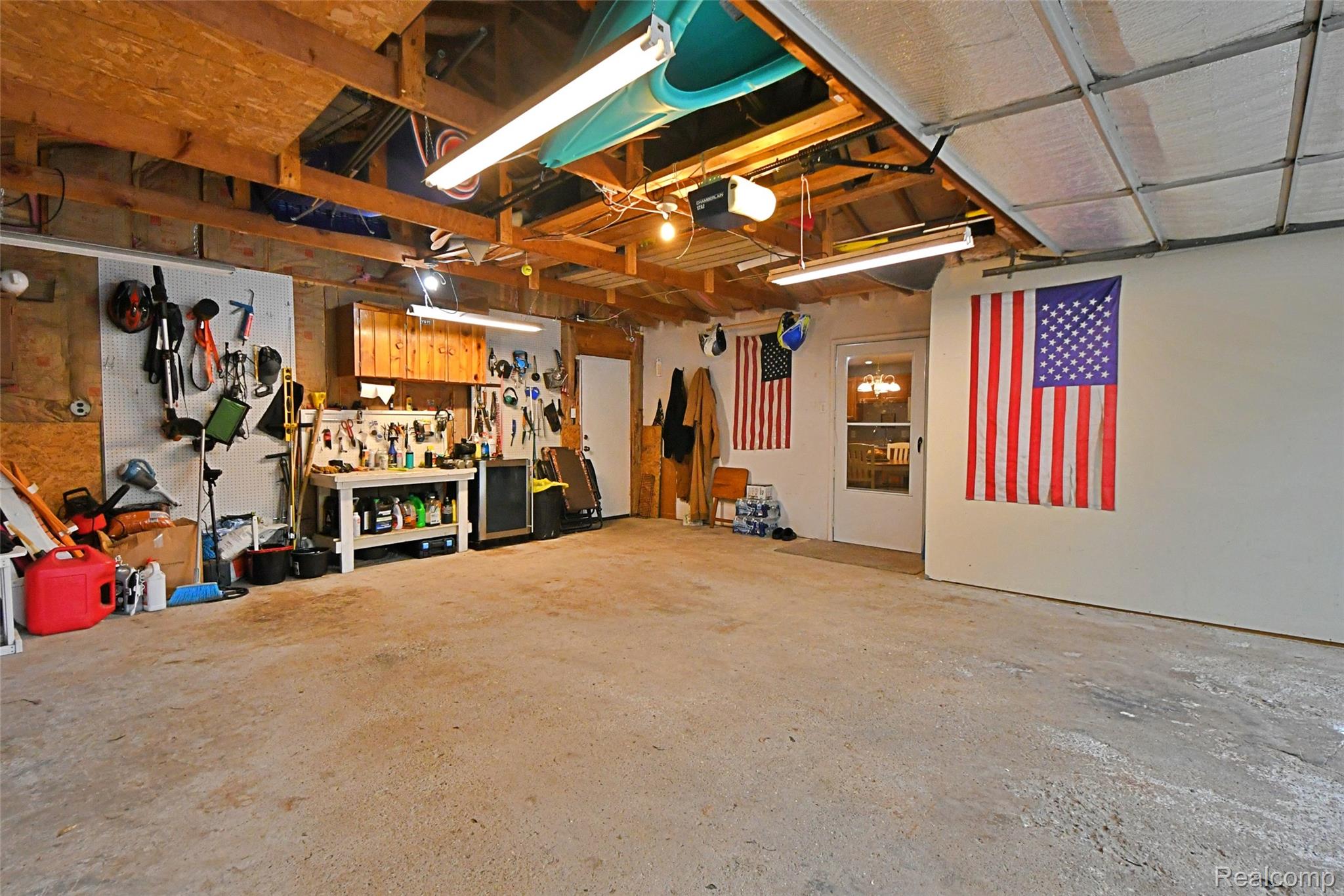 9611 Monroe Road St. Helen, MI 48656 - Photo 20 of 24 Spacious garage featuring a concrete floor, exposed wooden ceiling beams, and a built-in workbench with integrated cabinetry