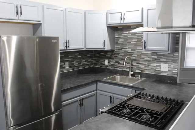 a kitchen with stainless steel appliances granite countertop a refrigerator stove sink and cabinets