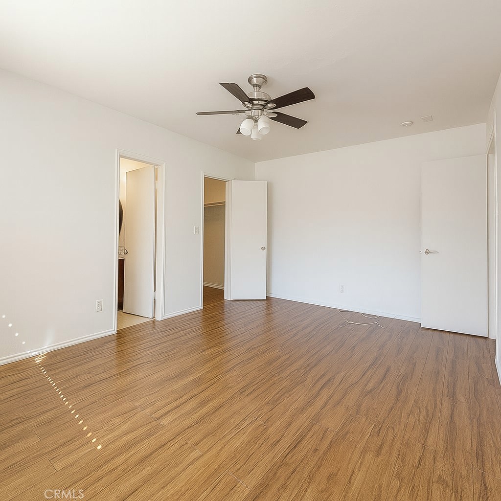 18619 Collins Street, Unit F29 Tarzana, CA 91356 - Photo 14 of 29 an empty room with wooden floor a ceiling fan and windows