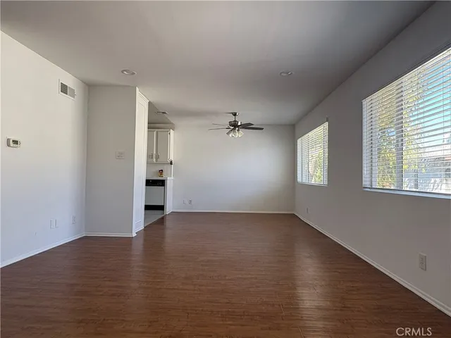 an empty room with wooden floor cabinet and windows