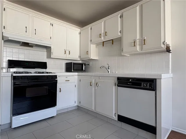 a kitchen with white cabinets and appliances