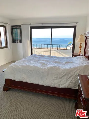 a bedroom with a bed and two large window