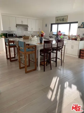 a open kitchen with stainless steel appliances kitchen island granite countertop a table and chairs in it