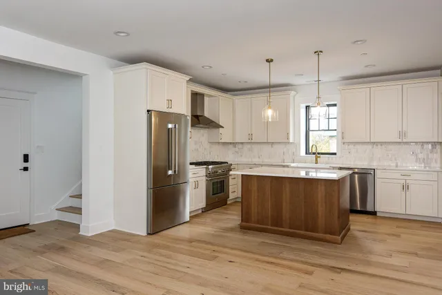 a kitchen with stainless steel appliances granite countertop a refrigerator a sink dishwasher a stove and white cabinets with wooden floor