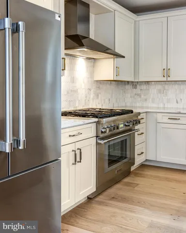 a kitchen with stainless steel appliances white cabinets and wooden floor