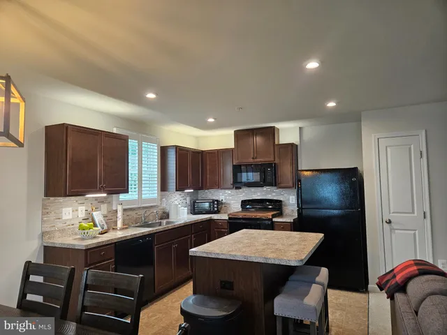 a kitchen with a refrigerator a stove a sink a dining table and chairs