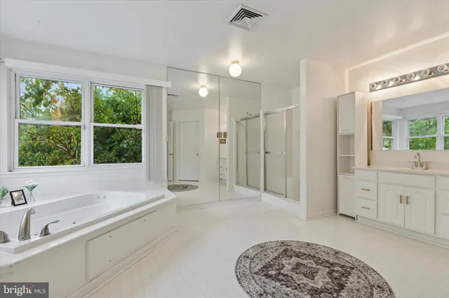 a spacious bathroom with a tub sink and mirror