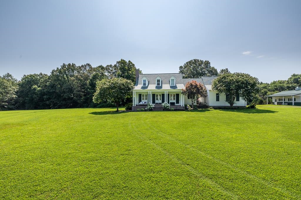 1915 Teague Store Road Somerville, TN 38068 - Photo 1 of 38 Expansive green lawn surrounds a white residence featuring dormer windows, a covered front porch with white columns, and dark shutters