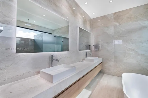 a bathroom with a white tub shower and sink