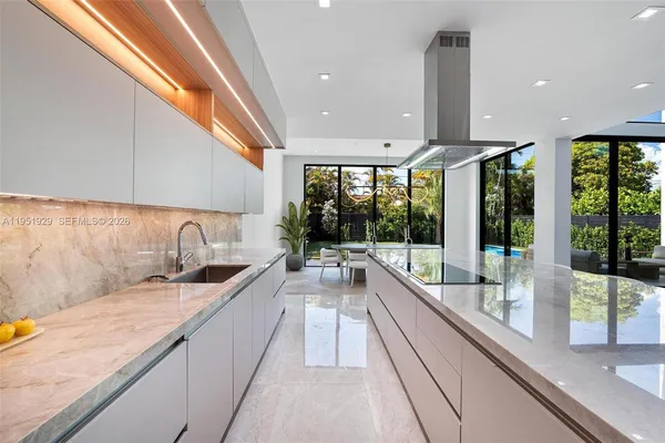 a large white kitchen with a large kitchen island sink and refrigerator
