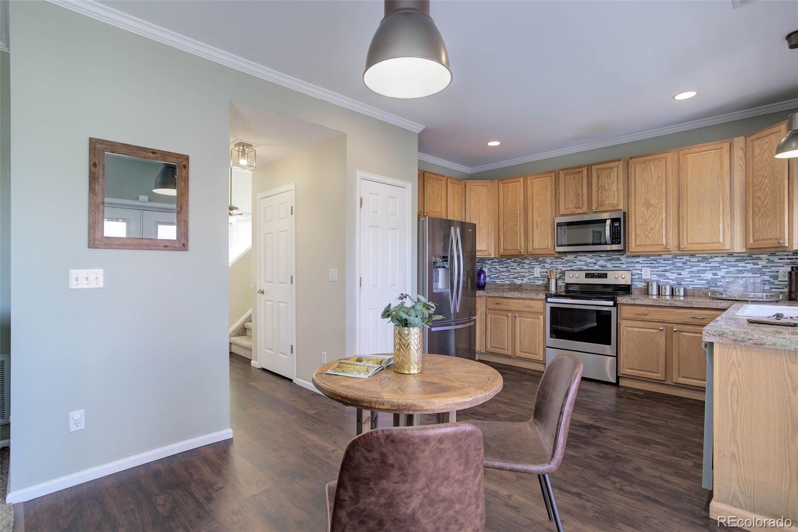 2471 South Andes Circle Aurora, CO 80013 - Photo 7 of 35 a kitchen with microwave a refrigerator and chairs
