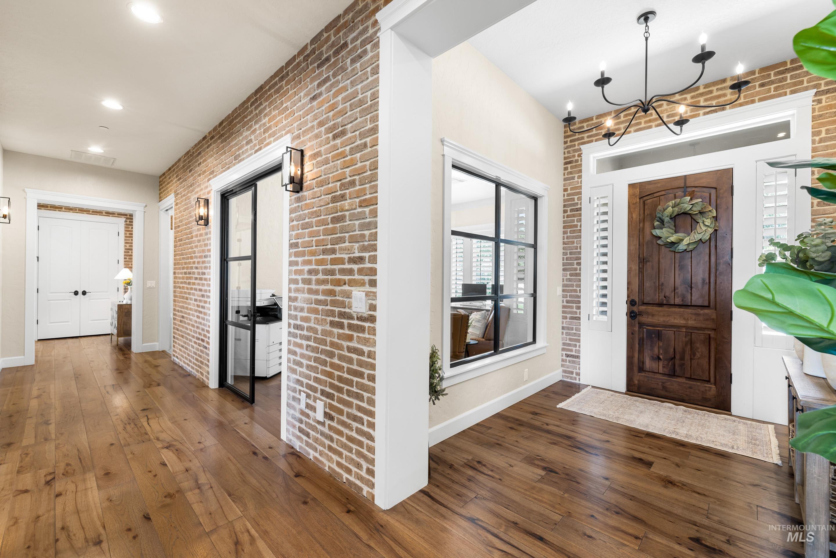 9819 Foothill Road Middleton, ID 83644 - Photo 10 of 50 Foyer entrance featuring brick wall, wood-type flooring, and a chandelier