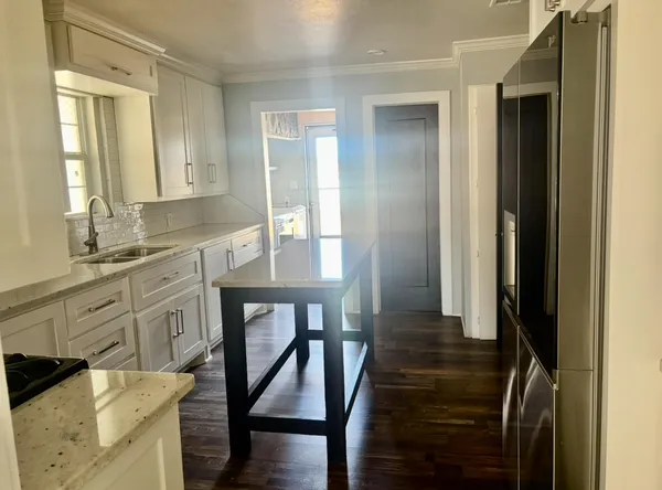 a kitchen with white cabinets and sink