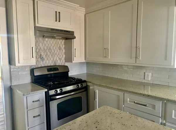 a kitchen with granite countertop white cabinets and stainless steel appliances