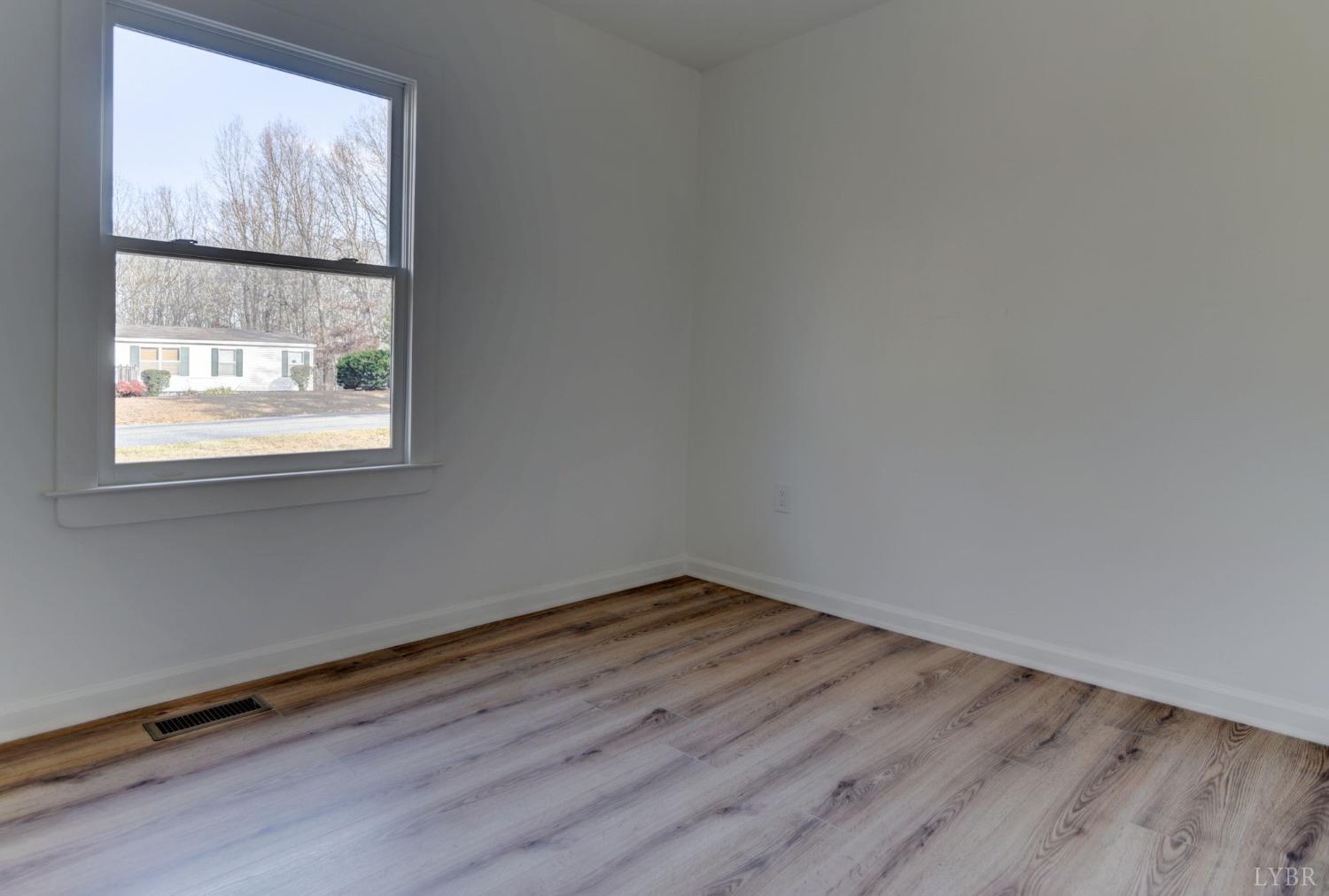 1252 Dearborn Road Evington, VA 24550 - Photo 16 of 31 an empty room with wooden floor and window