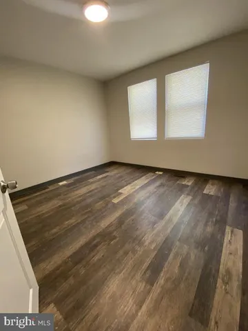an empty room with wooden floor cabinet and windows