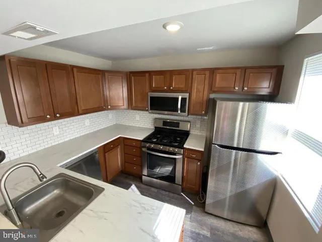 a kitchen with granite countertop a refrigerator and a stove top oven