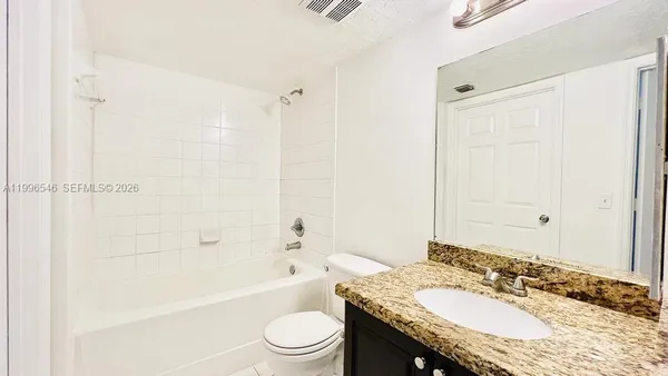 a bathroom with a granite countertop tub sink toilet and mirror