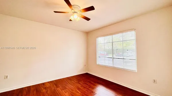 an empty room with a window and a fan