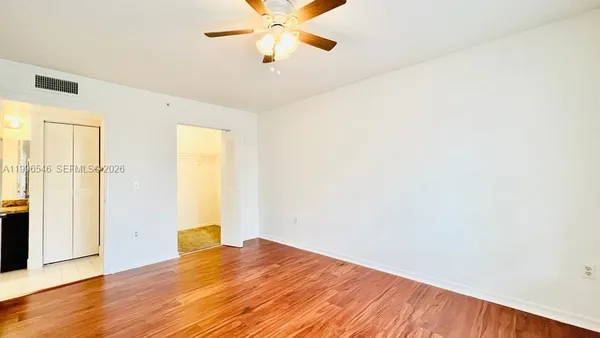 a view of empty room with wooden floor and fan