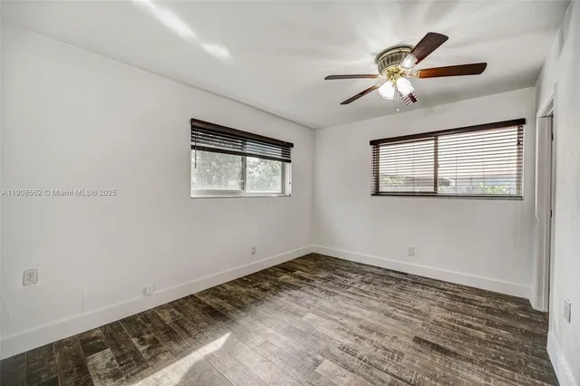 a view of a big room with wooden floor and windows