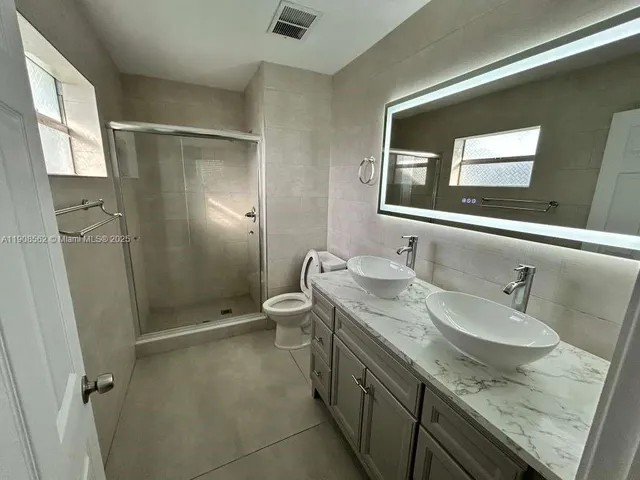 a bathroom with a granite countertop sink toilet and shower