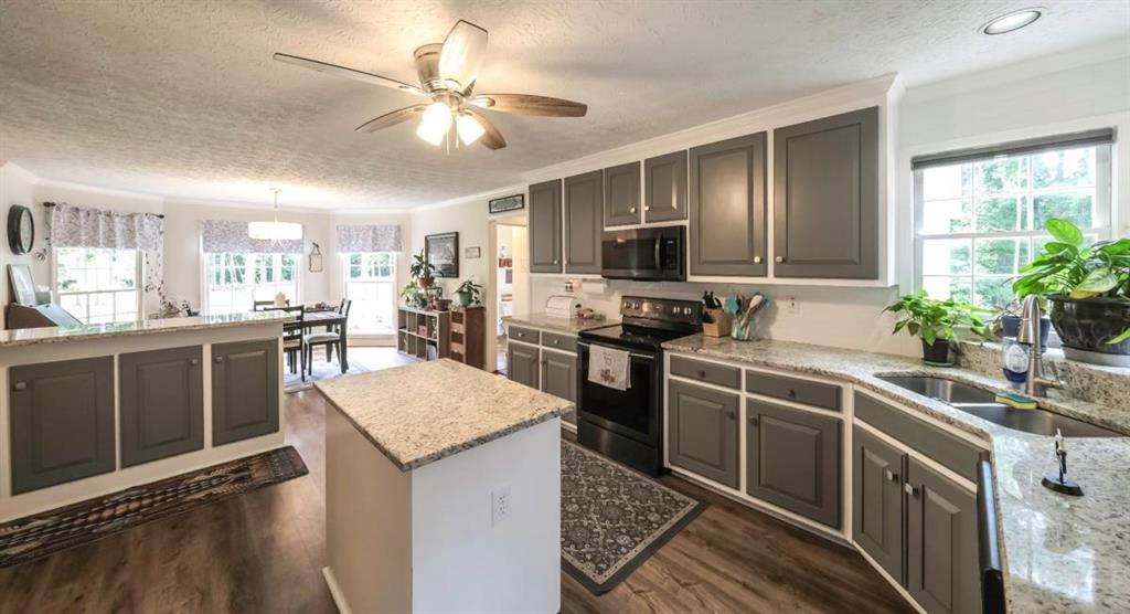 6945 John Rivers Road Fairburn, GA 30213 - Photo 49 of 65 a kitchen with kitchen island granite countertop stainless steel appliances a sink stove and refrigerator