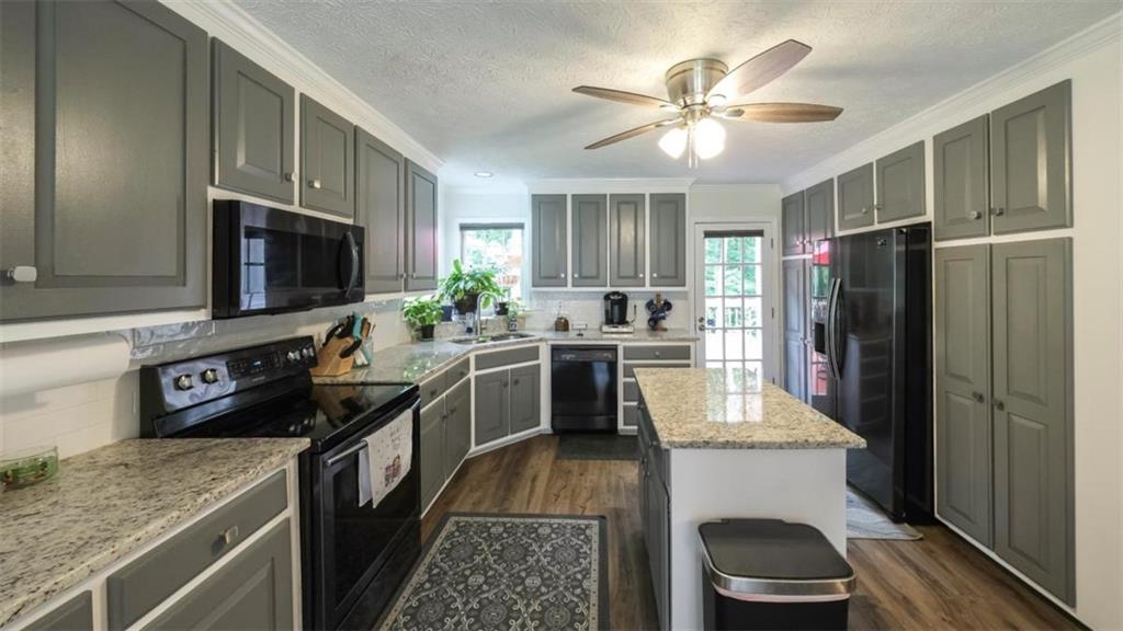 6945 John Rivers Road Fairburn, GA 30213 - Photo 57 of 65 a kitchen with kitchen island granite countertop a stove refrigerator and microwave