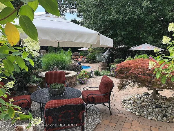 a backyard of a house with table and chairs under an umbrella
