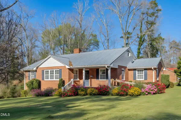 a front view of a house with a garden and trees