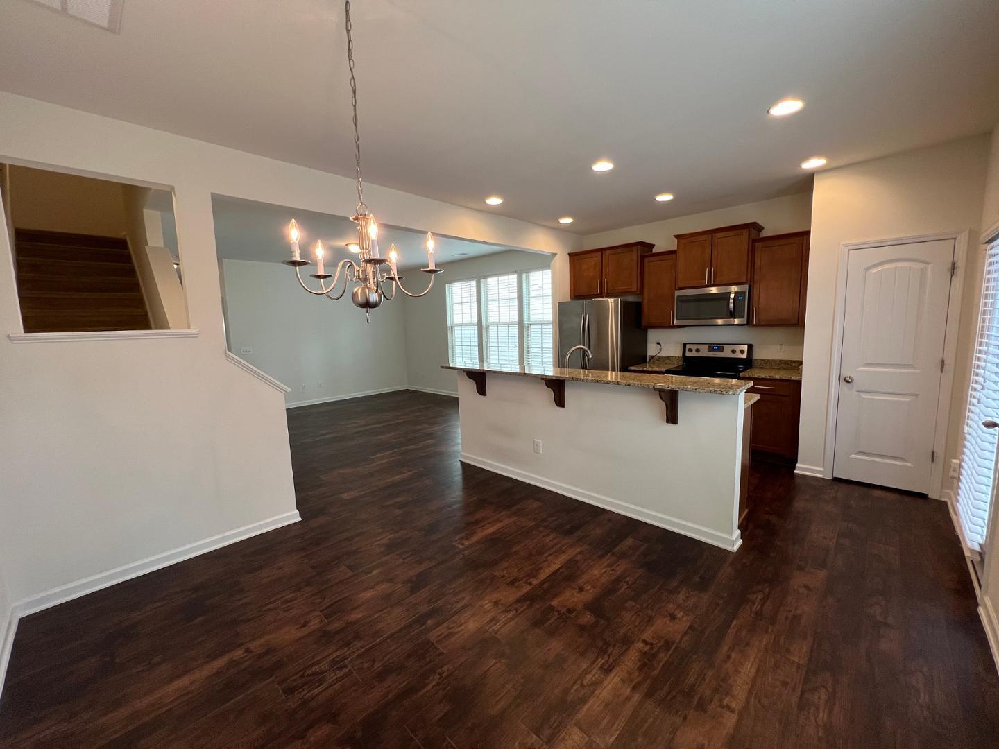 219 Cross Blossom Road Durham, NC 27703 - Photo 9 of 35 a large white kitchen with kitchen island a stove a sink dishwasher and a refrigerator with wooden floor